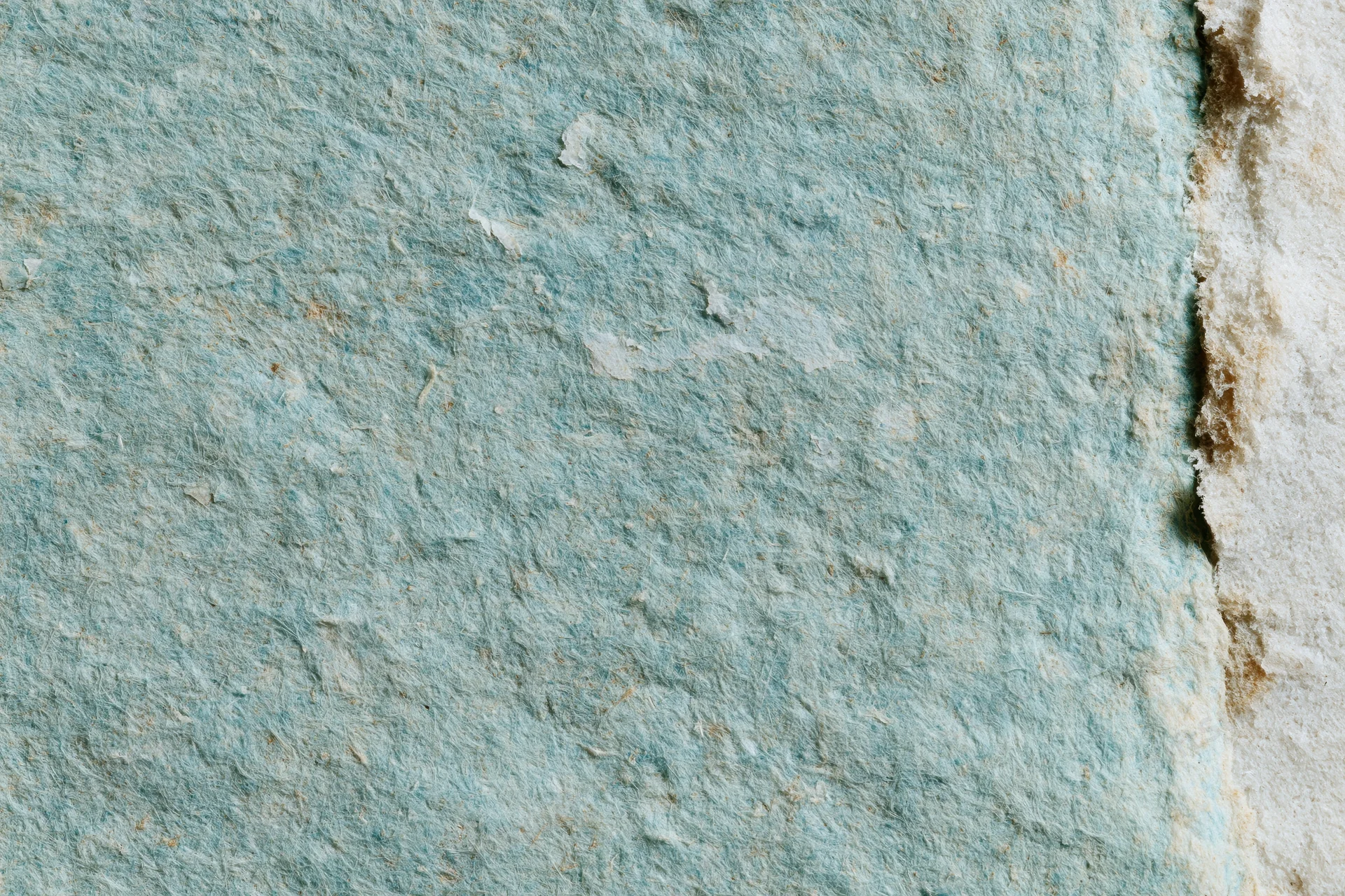 Close-up of aged turquoise paper surface with textured, weathered finish and peeling edges