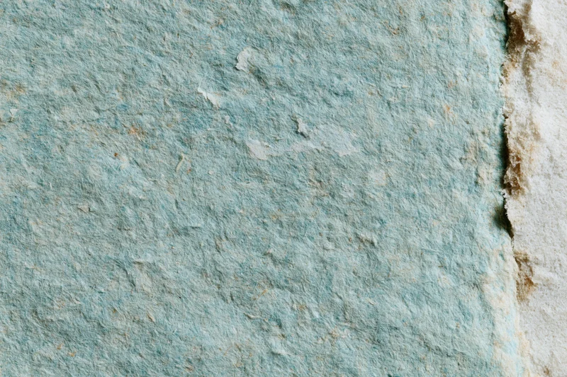Close-up of aged turquoise paper surface with textured, weathered finish and peeling edges