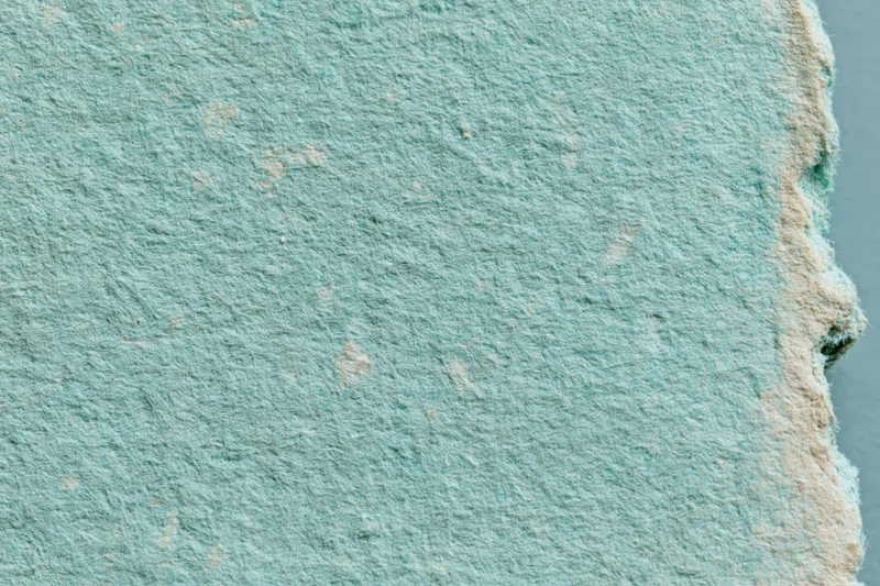 Close-up of aged turquoise paper surface with textured fiber and worn edges in flat lay arrangement