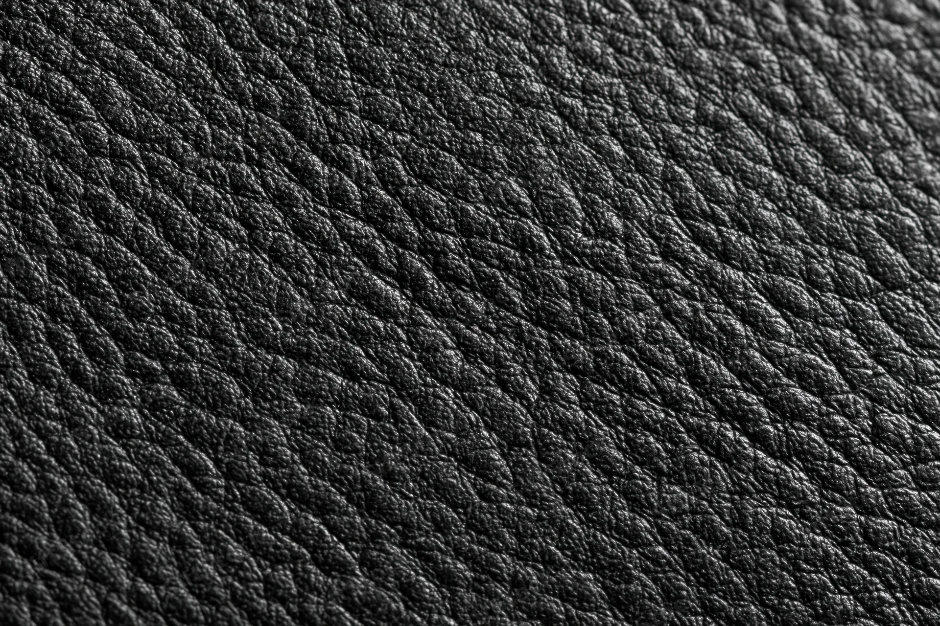 Close-up of black genuine leather surface with visible grain pattern filling the frame