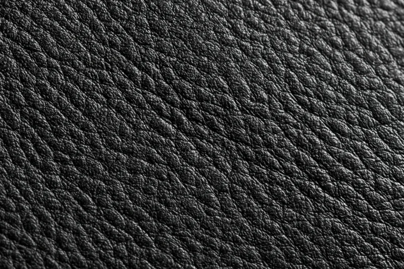 Close-up of black genuine leather surface with visible grain pattern filling the frame