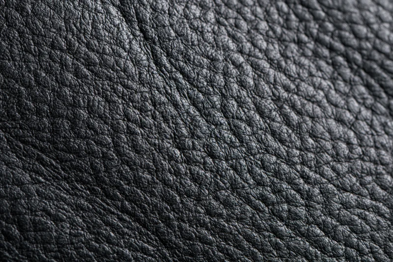 Close-up of black genuine leather surface showing natural grain texture