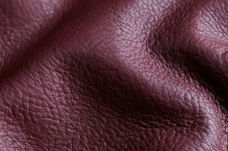 Close-up of deep burgundy genuine leather surface showing natural grain and texture