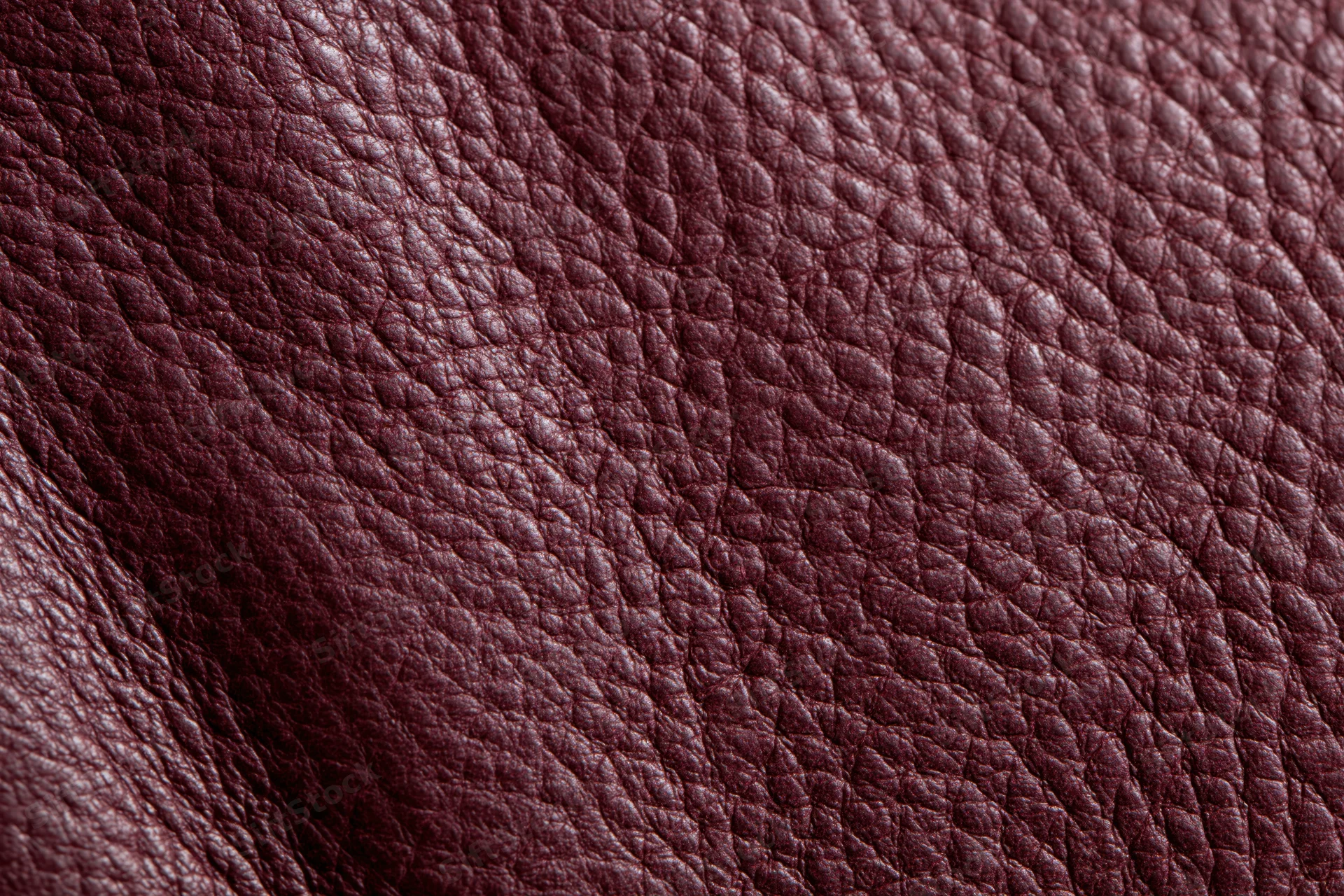 Close-up of deep burgundy genuine leather surface showing natural grain texture