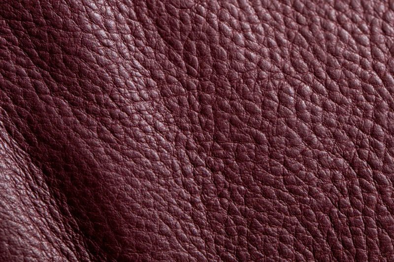 Close-up of deep burgundy genuine leather surface showing natural grain texture