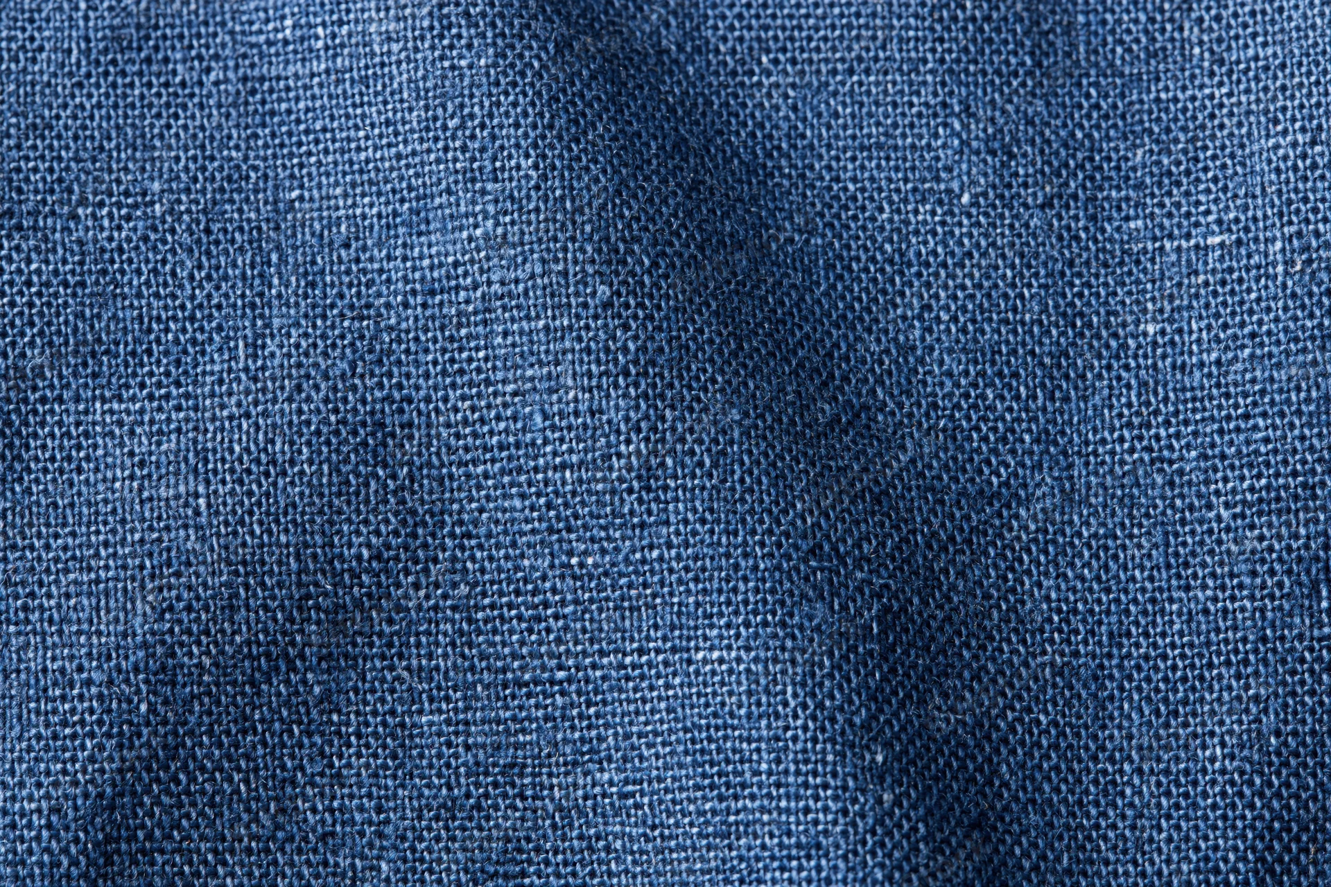 Close-up of navy blue woven denim fabric filling the frame in a flat lay arrangement