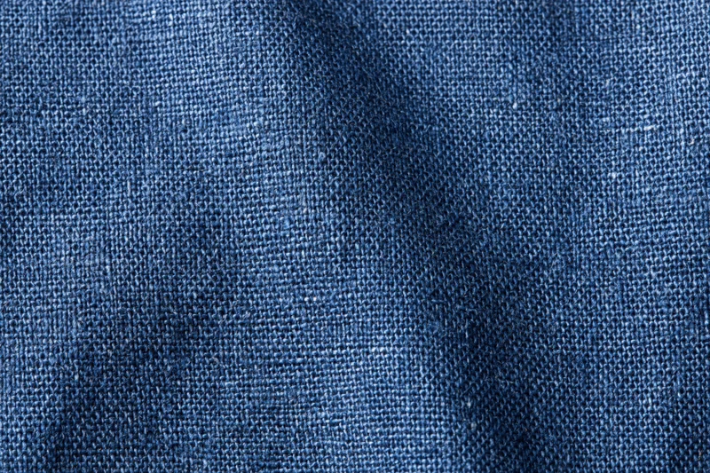 Close-up of navy blue woven denim fabric filling the frame in a flat lay arrangement
