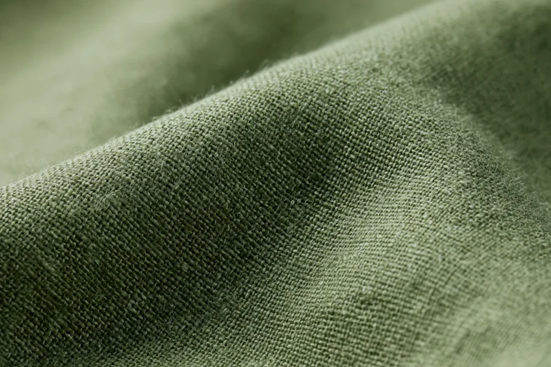 Close-up of olive green linen fabric with visible weave texture filling the frame