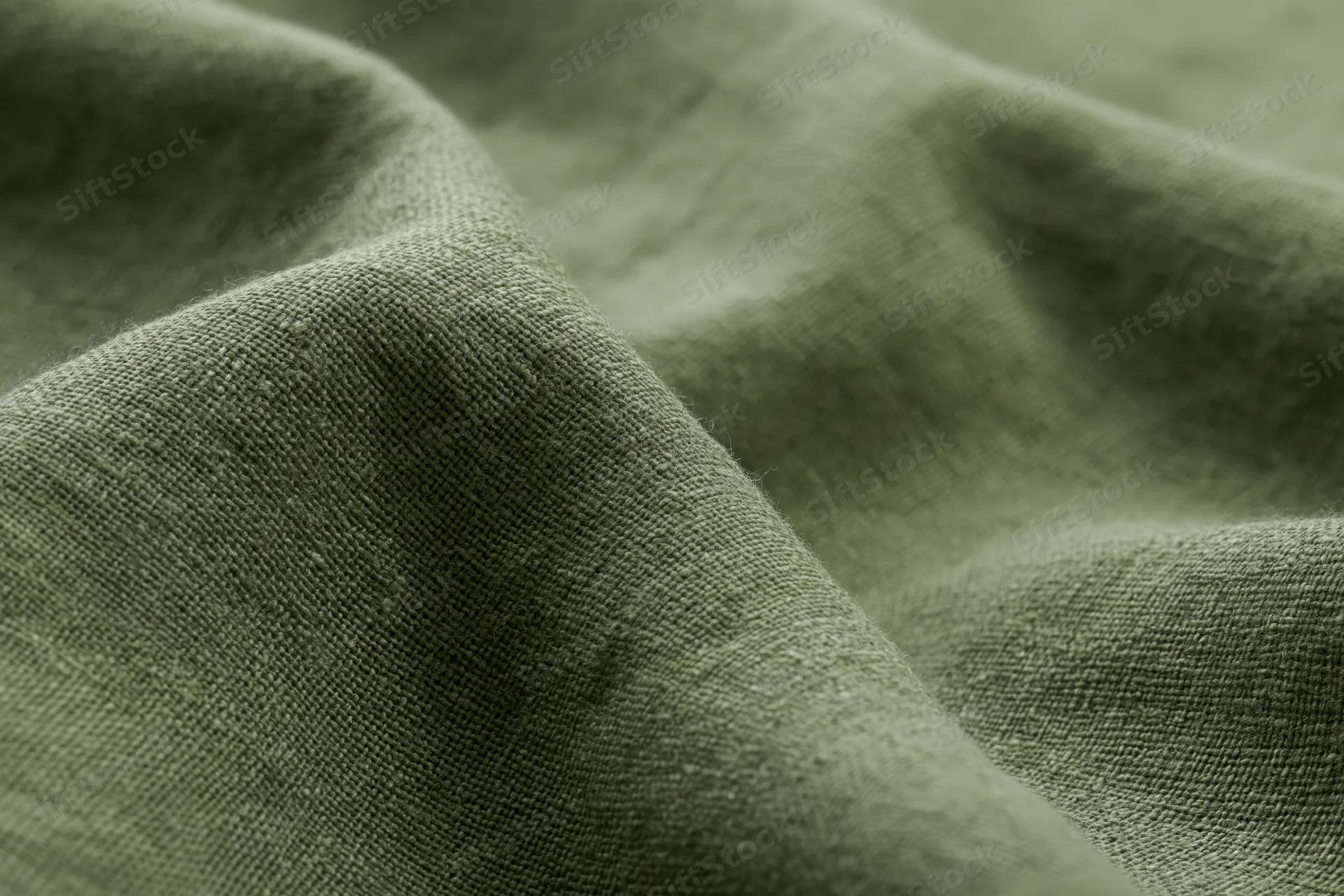 Close-up of olive green linen fabric with visible weave and soft folds filling the frame