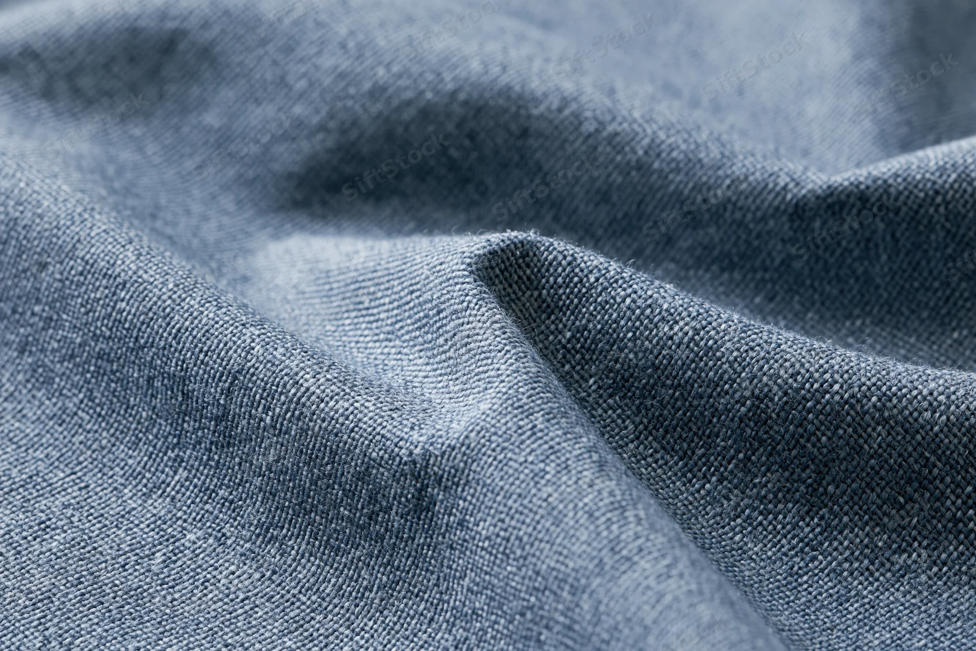 Close-up of blue woven fabric with visible texture and folds filling the frame