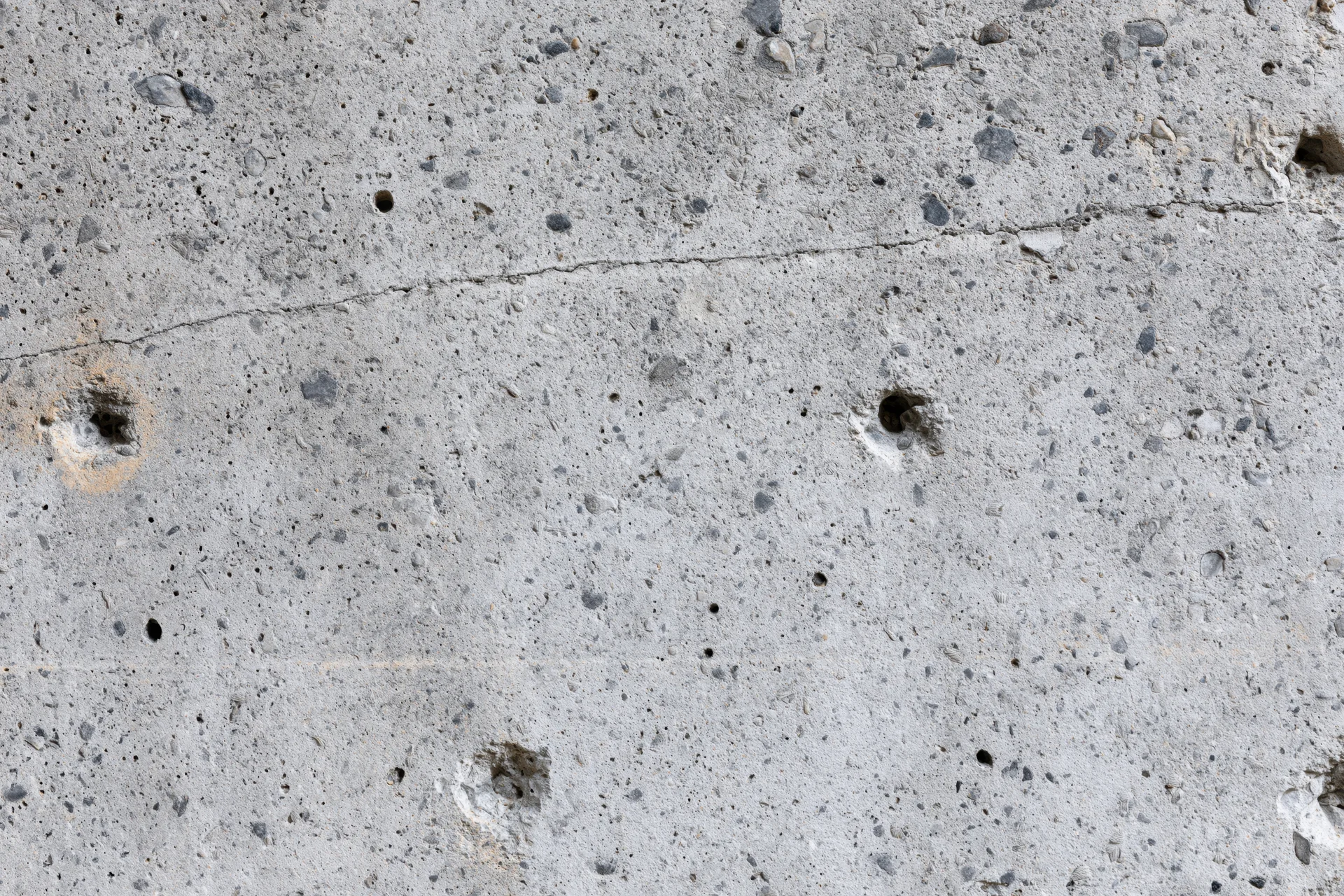 Close-up of a rough concrete wall surface with holes and cracks showing texture and construction details
