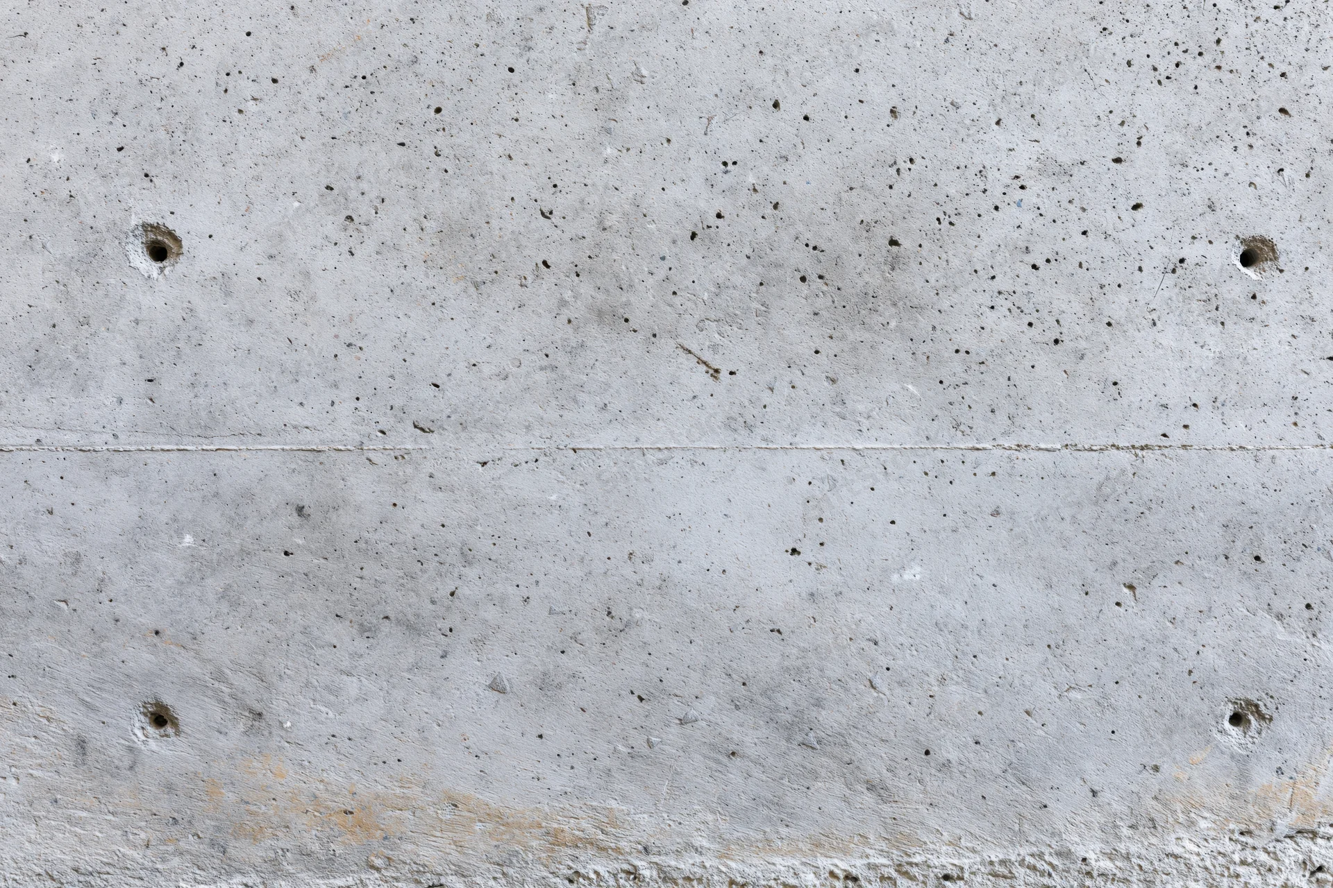 Close-up of a bare concrete wall surface with visible texture and formwork holes