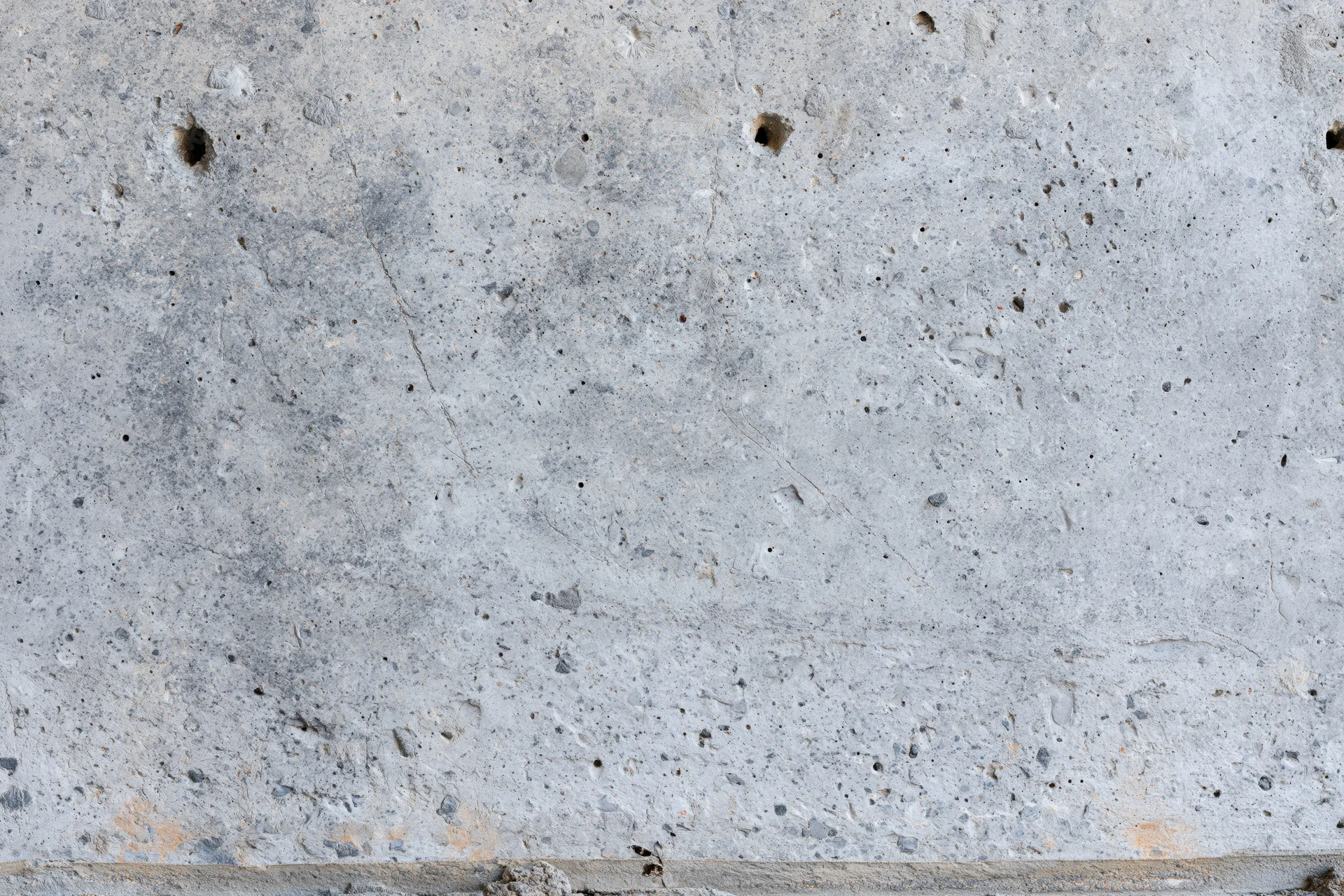 Close-up of a rough concrete wall surface with visible holes and cracks
