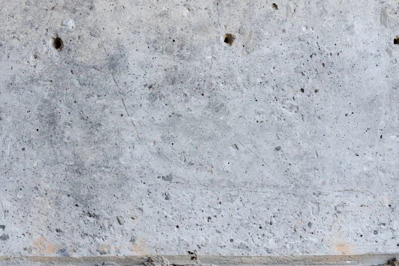 Close-up of a rough concrete wall surface with visible holes and cracks