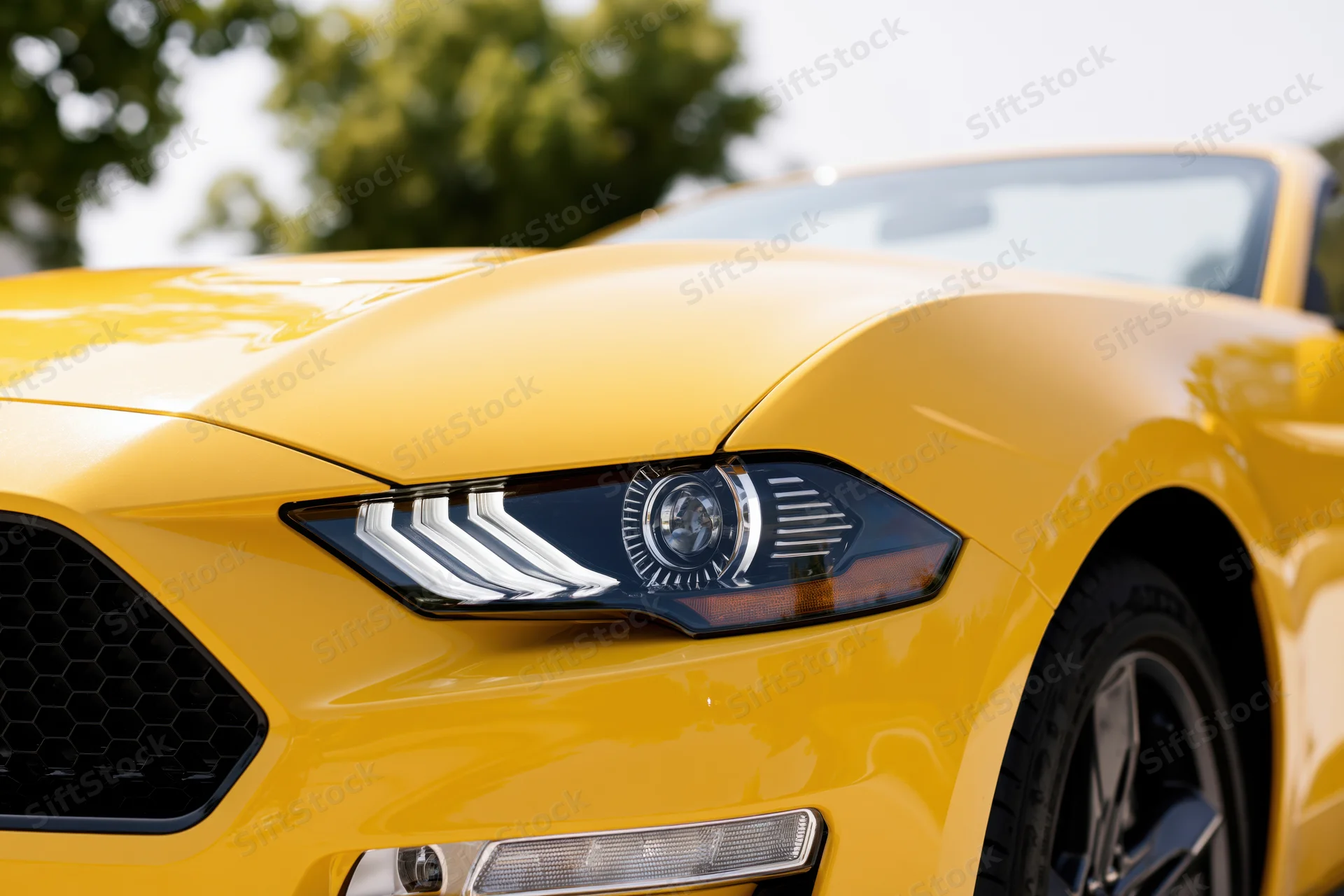 Close-up front quarter view of a yellow ford mustang convertible showing headlight grille and wheel