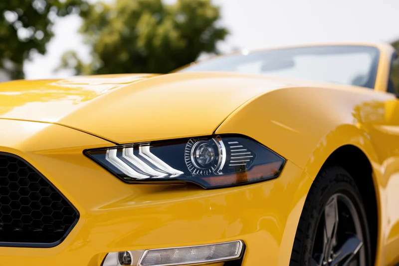 Close-up front quarter view of a yellow ford mustang convertible showing headlight grille and wheel