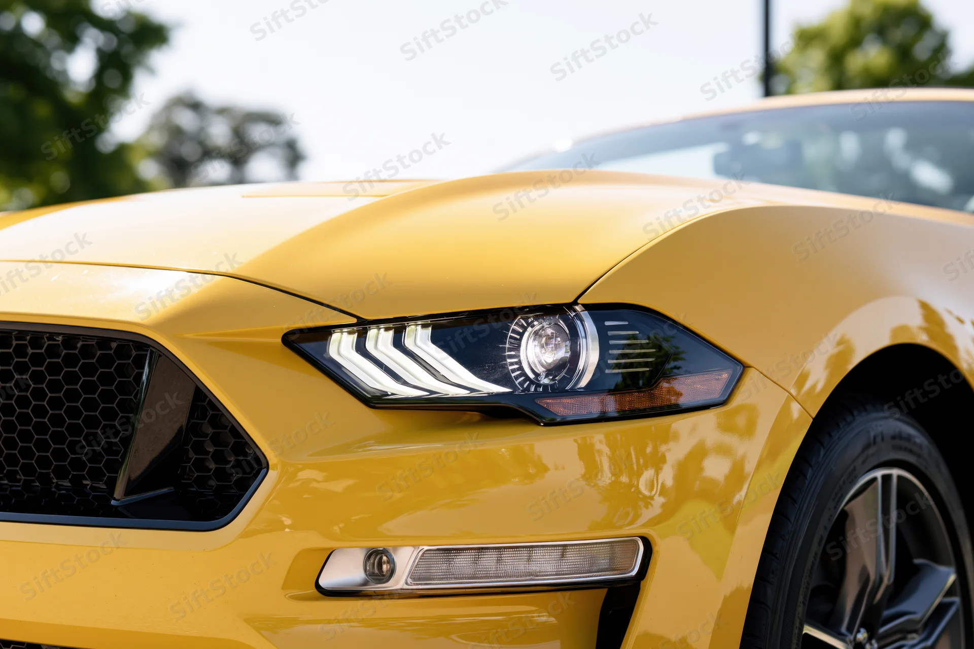 Close-up front quarter view of a yellow ford mustang convertible showing headlight grille and wheel