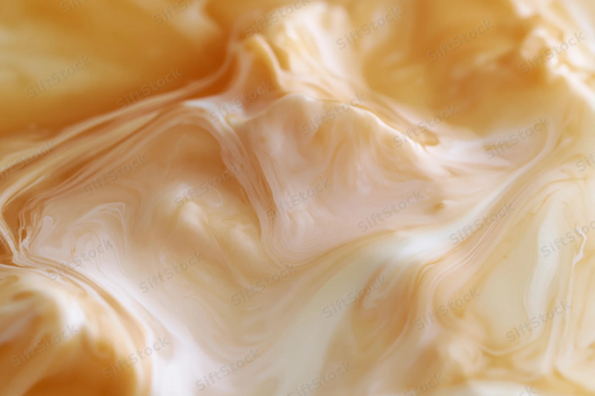 Caramel and cream swirling together in a smooth, glossy flow