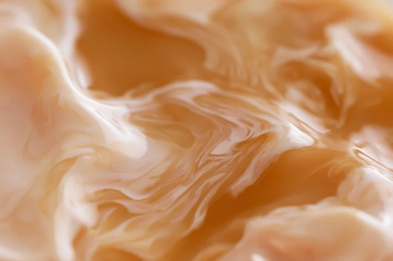 Cream swirling into warm caramel in a close-up macro view