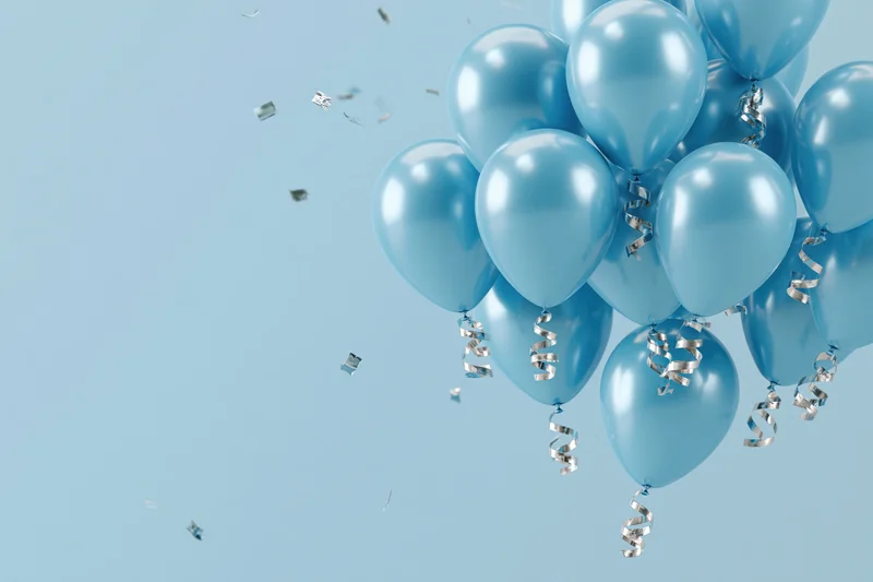 Cluster of shiny cyan helium balloons with curling silver ribbons floating against a light blue background