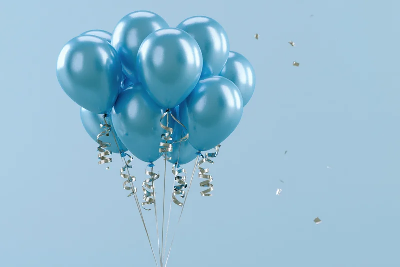 Cluster of shiny cyan helium balloons with curling silver ribbons floating against a light blue background with scattered gold confetti