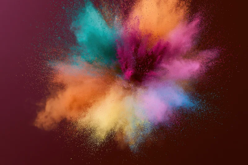 Colorful holi powder bursting outward in mid-air against dark background