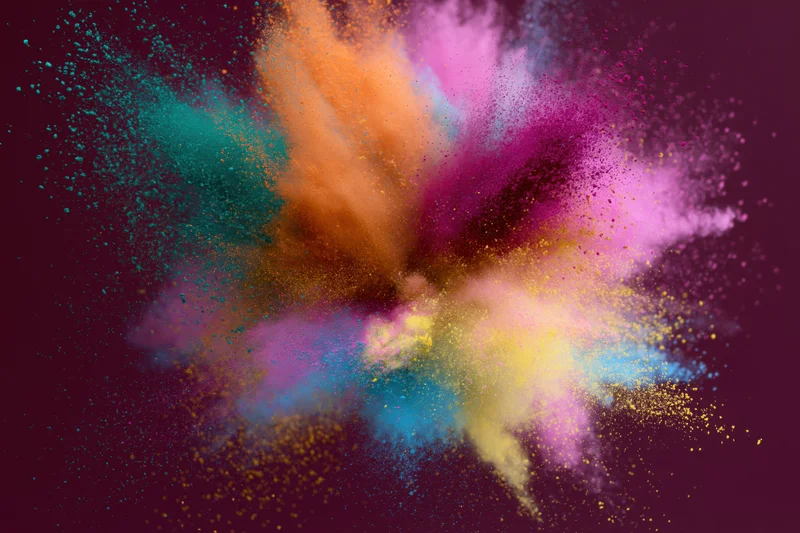 Colorful holi powder bursting outward in dynamic explosion against dark background