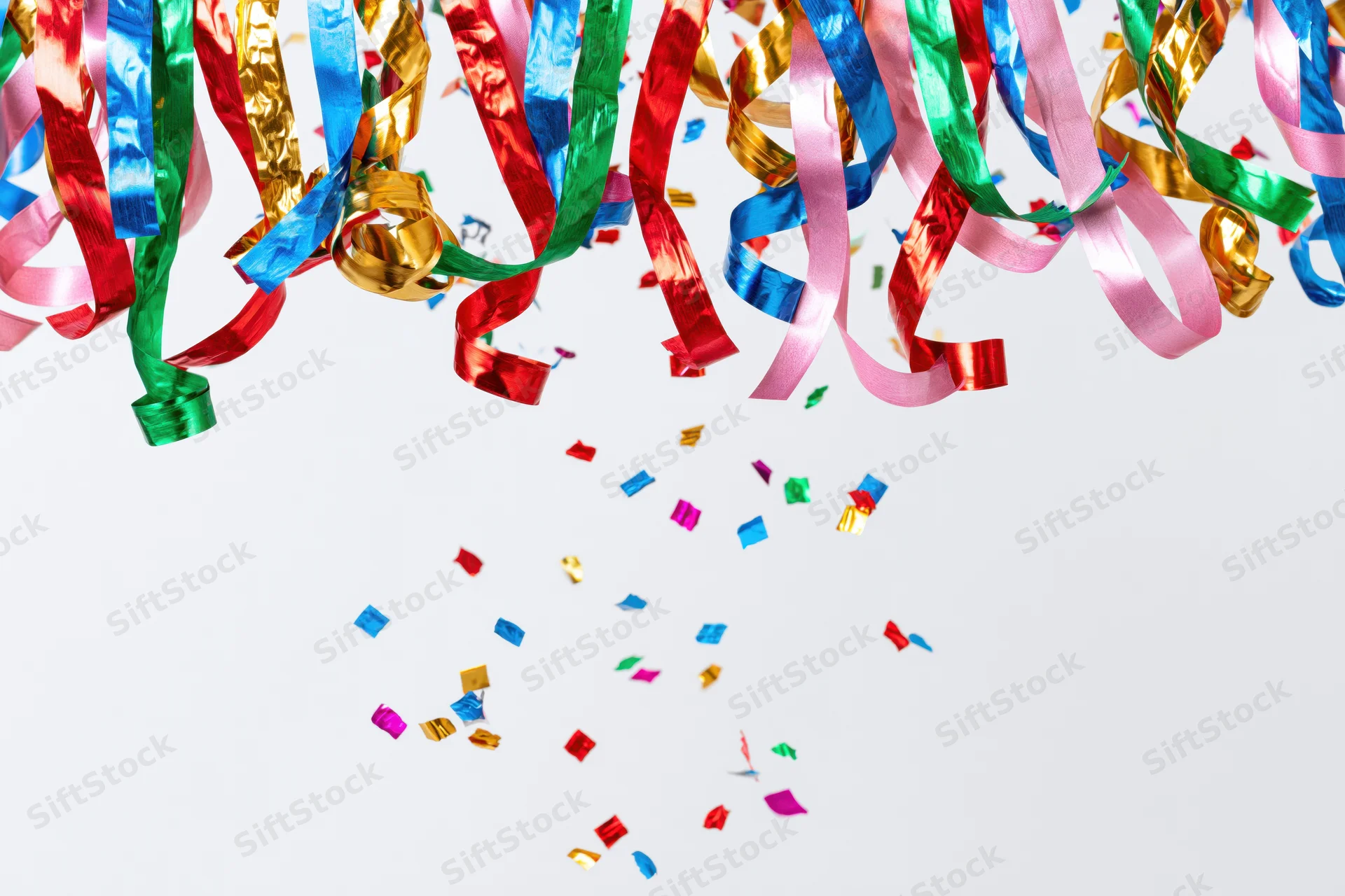 Colorful metallic party streamers and confetti falling against a white background with copyspace
