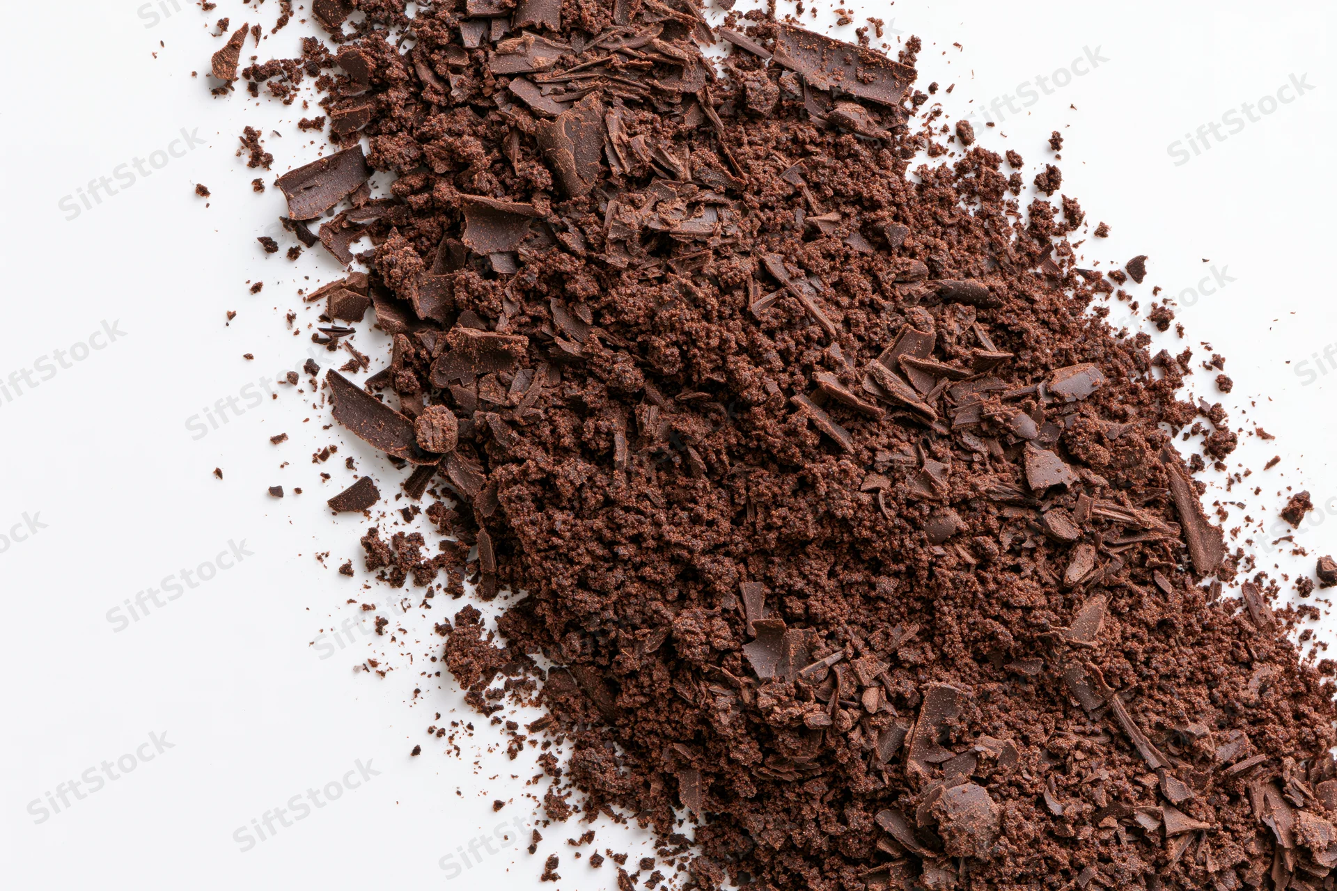 Dark chocolate shavings and coarse crumbles scattered across a white surface