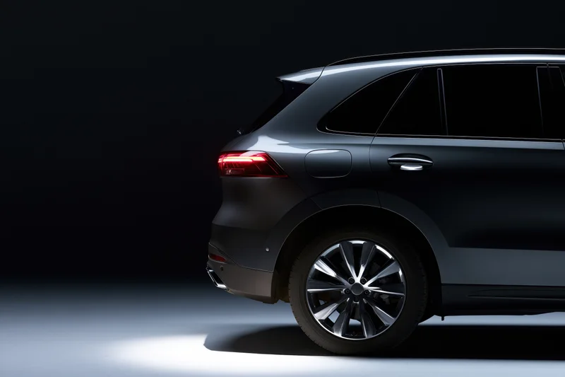 Dark grey luxury suv shown from rear threequarter angle in studio lighting with spotlight and shadow on floor