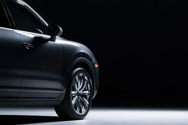 Dark grey luxury suv shown from rear threequarter angle in studio lighting with copyspace
