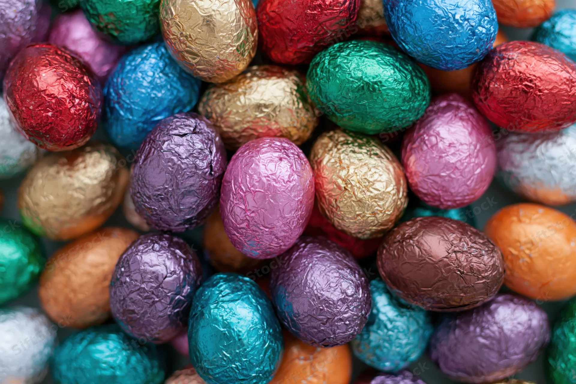 Foil-wrapped chocolate easter eggs packed tightly together in a colorful arrangement