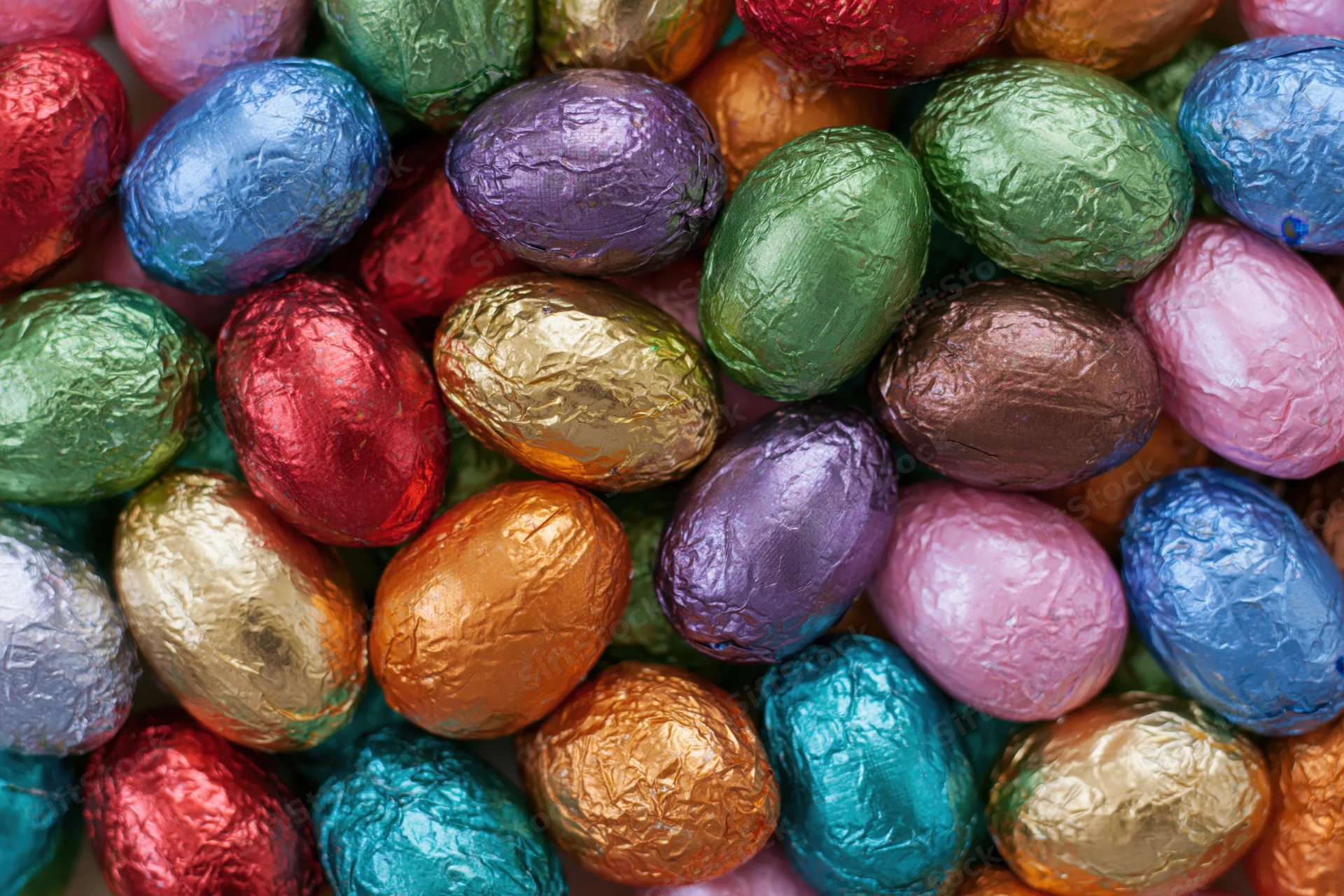 Foil-wrapped chocolate easter eggs packed tightly together