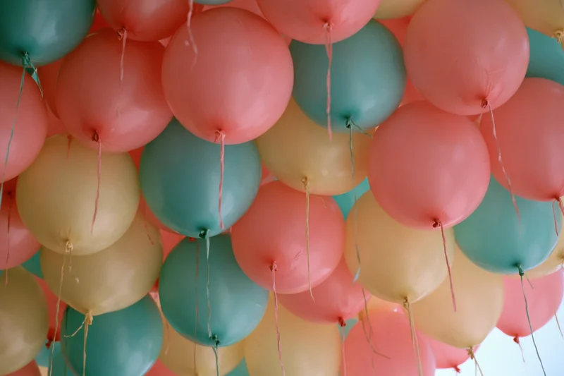 Cluster of inflated balloons in coral pink teal and soft yellow arranged as a decorative wall