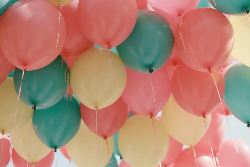 Cluster of inflated balloons in coral pink teal and soft yellow arranged as decoration for a celebration