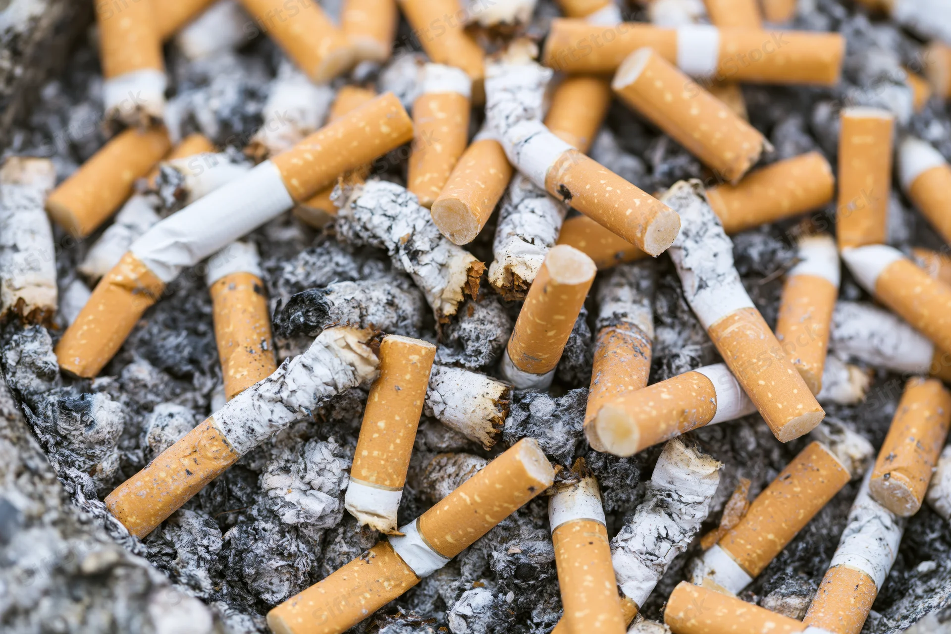 Cigarette butts piled in a public ashtray