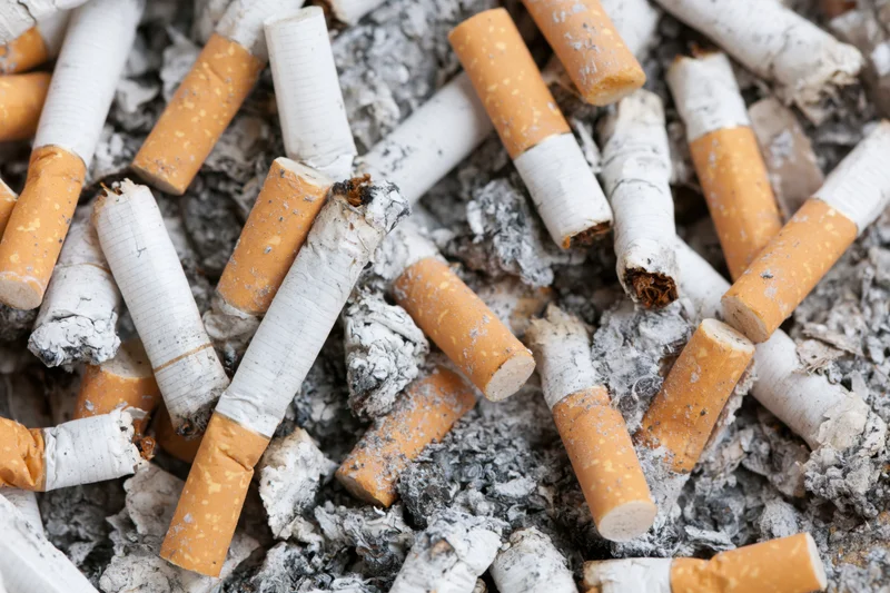 Used cigarette butts piled in a public ashtray