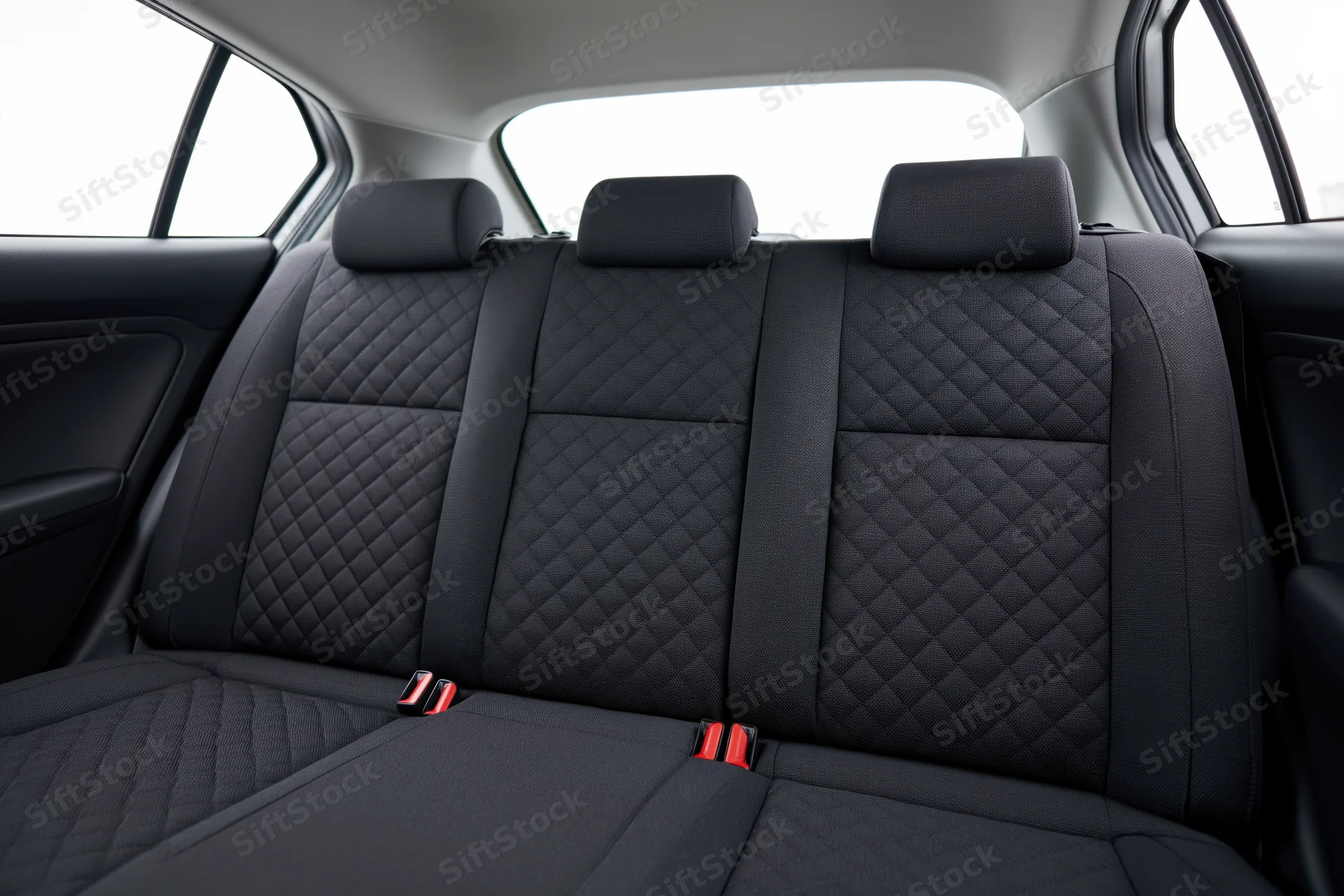 Rear bench seat with quilted black upholstery and red buckle details in a compact car interior