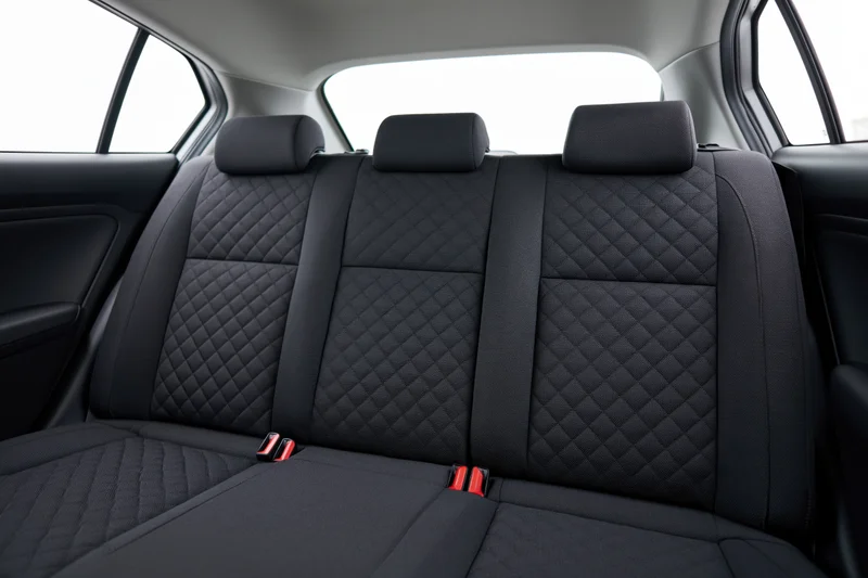 Rear bench seat with quilted black upholstery and red buckle details in a compact car interior