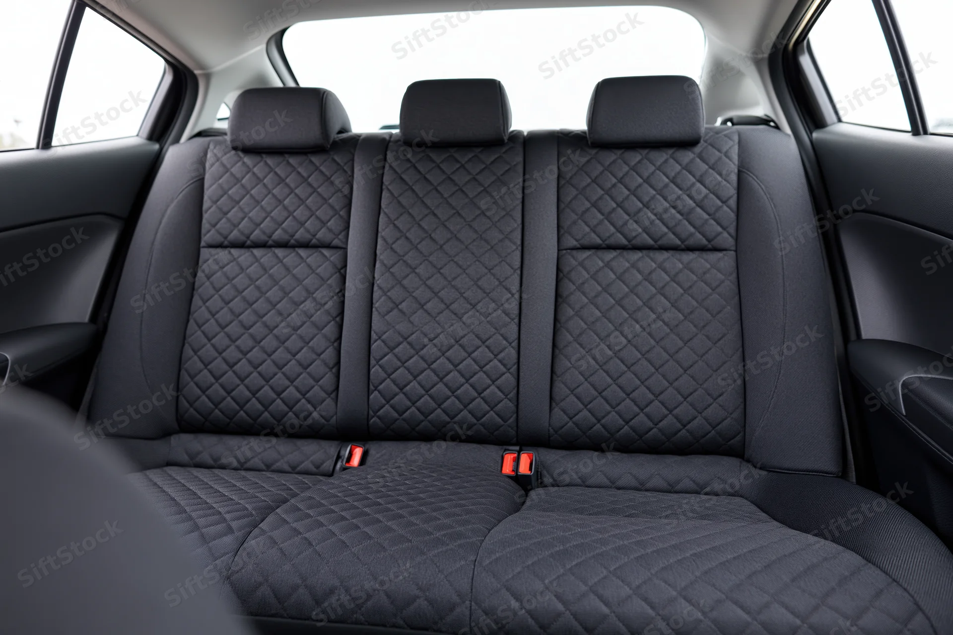 Empty rear bench seat with quilted black fabric upholstery in a compact car interior