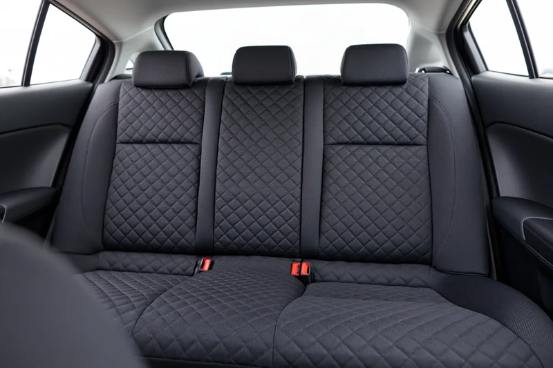 Empty rear bench seat with quilted black fabric upholstery in a compact car interior