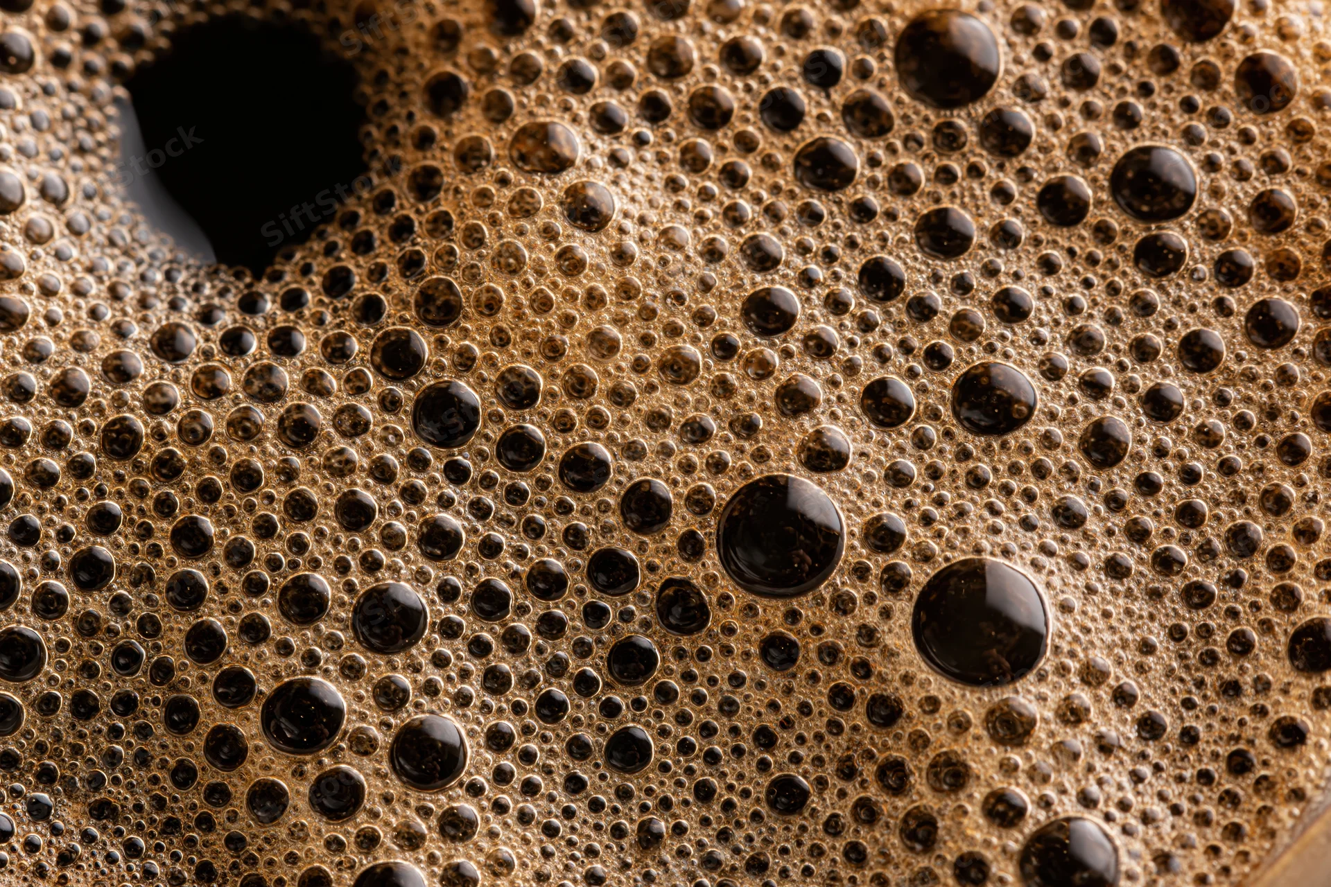 Close-up of black coffee surface covered in foam and bubbles