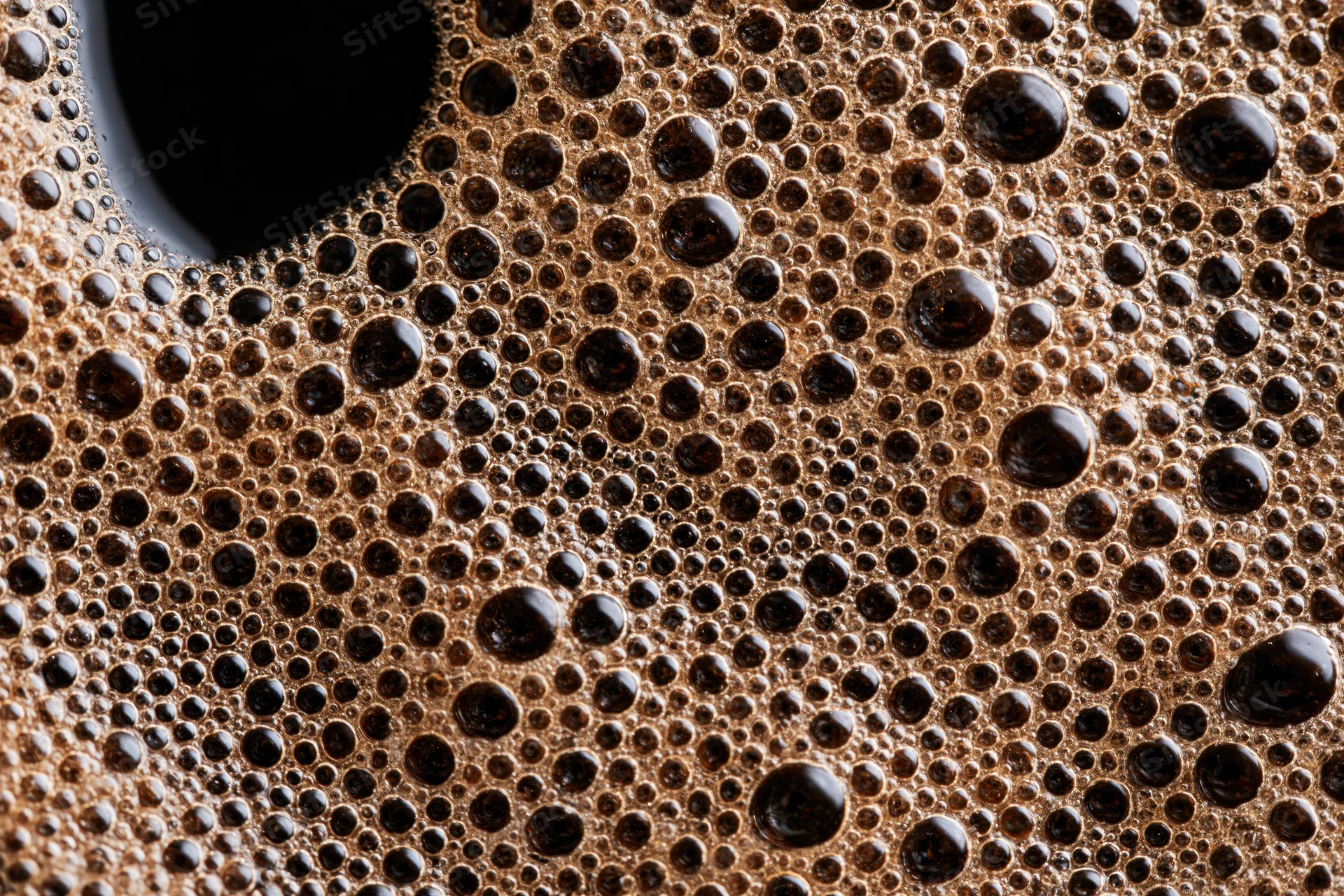 Closeup of fresh black coffee surface covered in foam and bubbles
