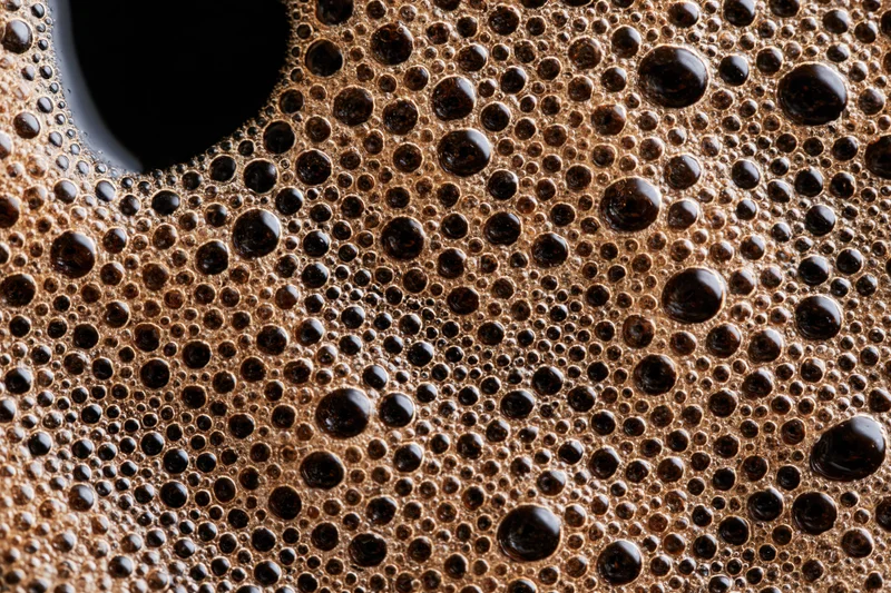 Closeup of fresh black coffee surface covered in foam and bubbles