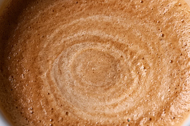 Coffee crema with swirling foam pattern filling the frame in extreme closeup overhead view