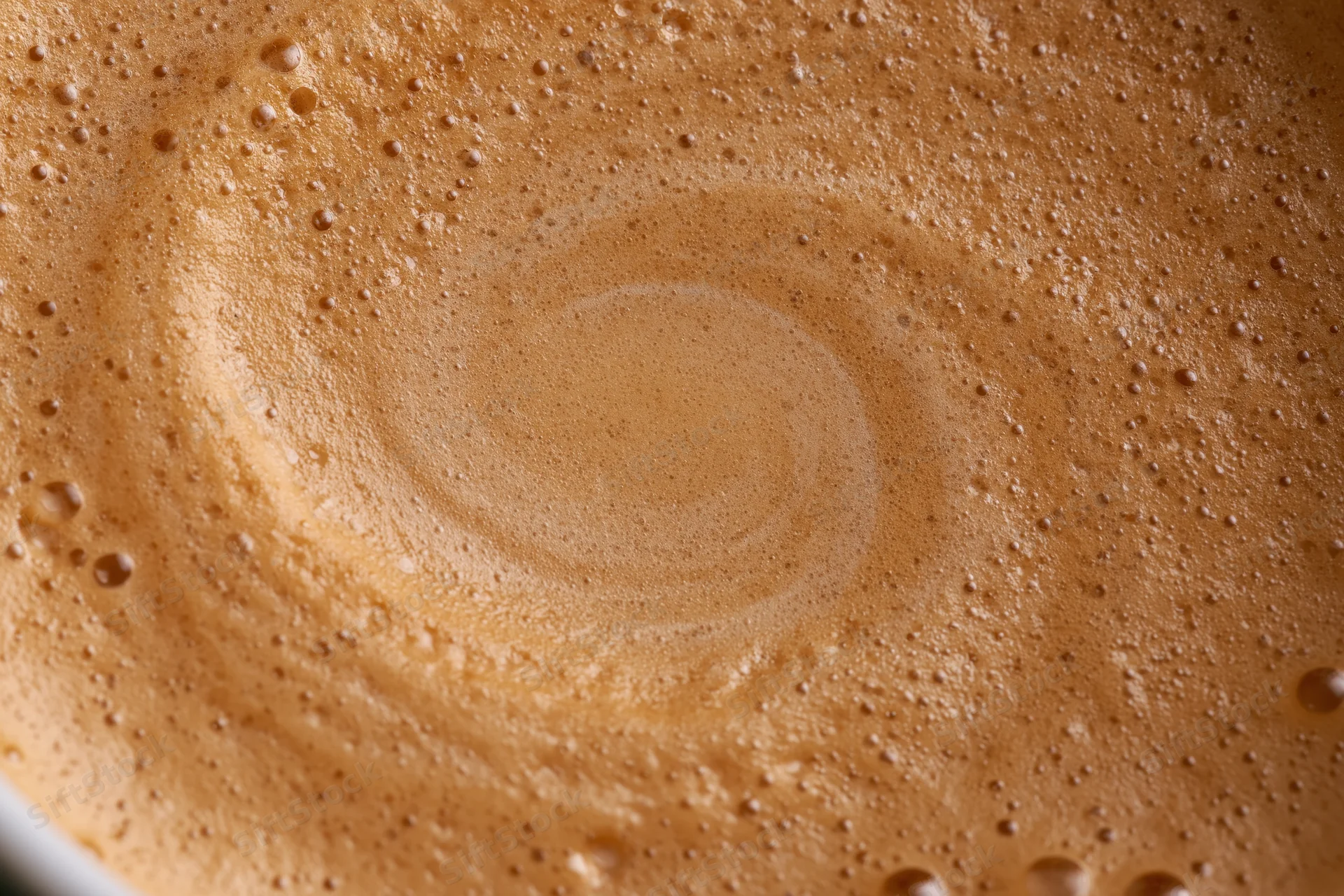 Coffee crema with swirling foam and bubbles filling the frame in extreme closeup overhead view