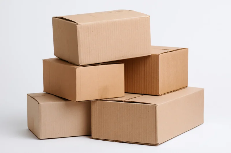 Five plain cardboard boxes of varying sizes stacked in a pyramid formation on a white background