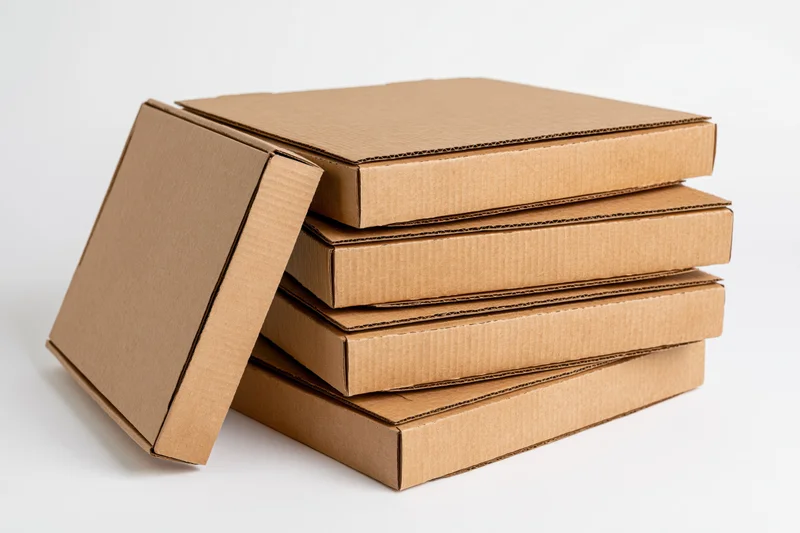 Stack of plain corrugated cardboard pizza boxes arranged vertically on white background with one lid open