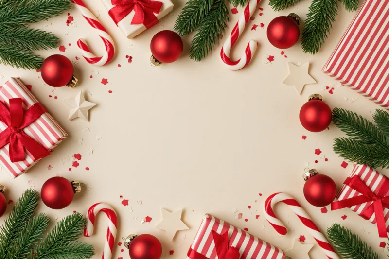 Christmas decorations arranged in a border frame on a light surface with copyspace in center