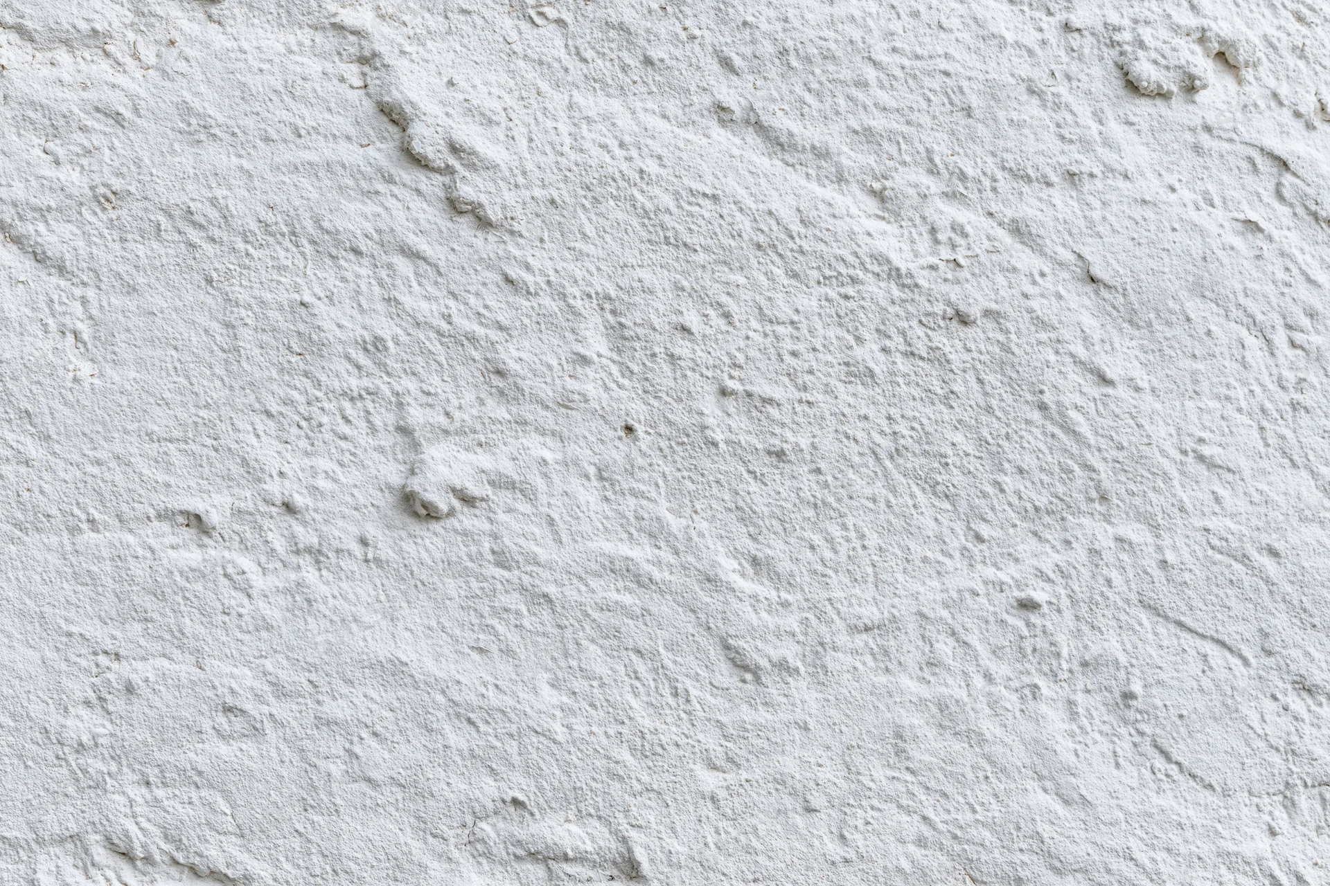 White painted concrete wall surface filling the frame with rough texture and even lighting
